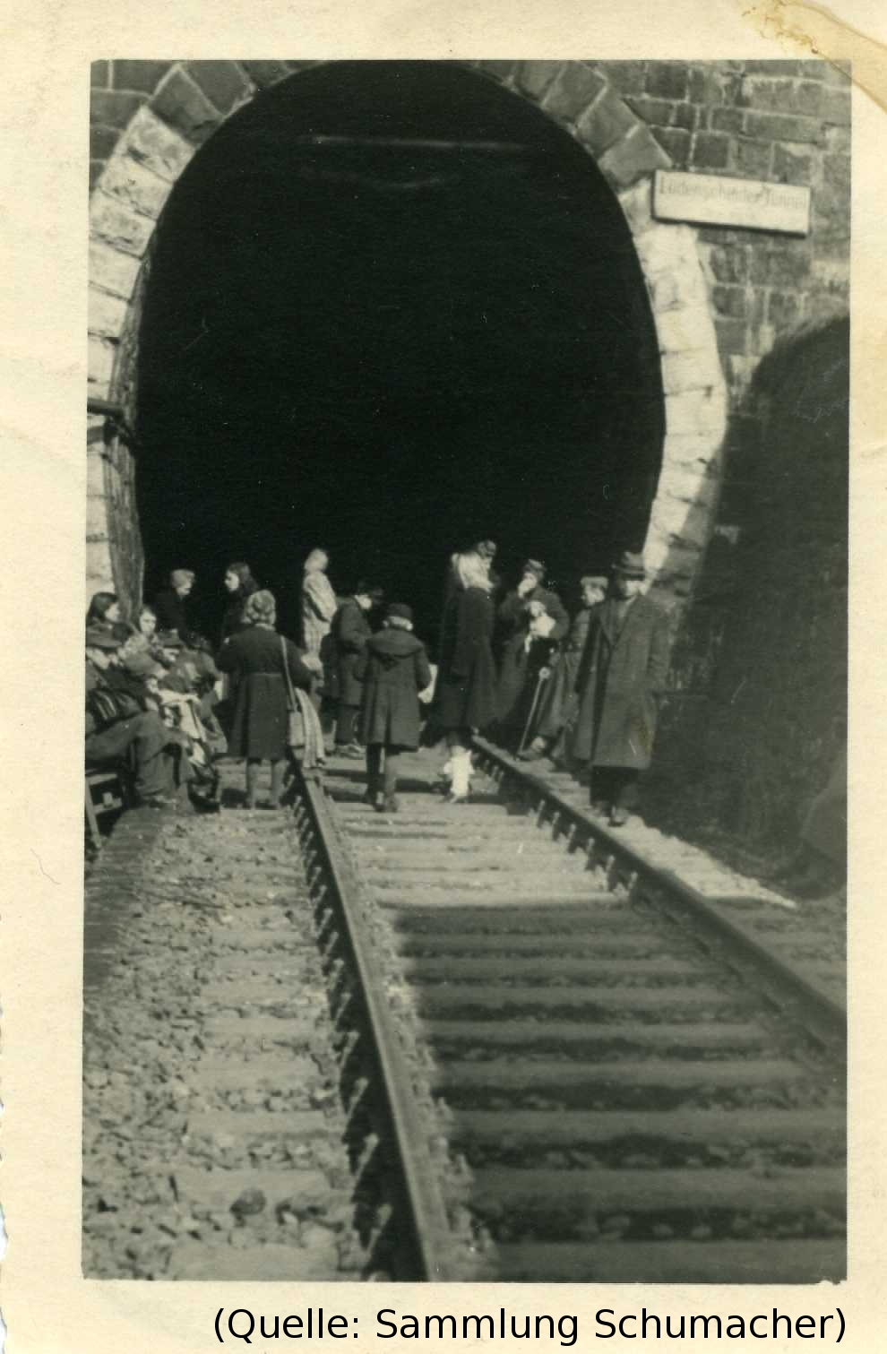 Foto: Blick in einen Eisenbahntunnel. Menschen gehen hinein.
