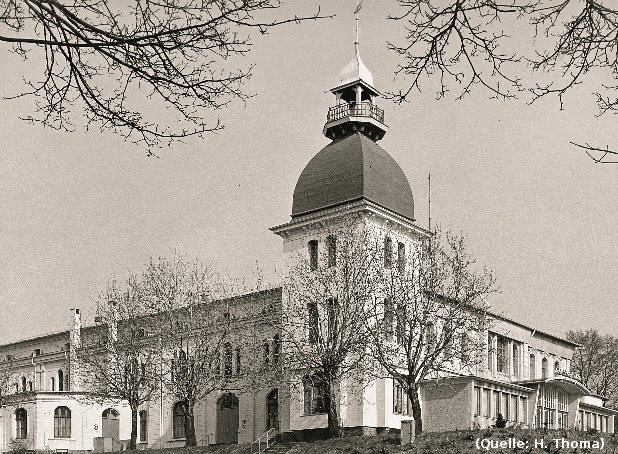 Foto: Eine Halle mit einem Eckturm und einem breiten Eingangsvorbau