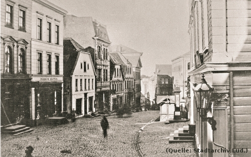 Foto: Blick in eine mit Kopfsteinen gepflasterte Strasse. Rechts und links Häuser.