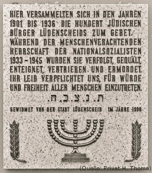 Foto: Eine Tafel. Text:'Hier versammelten sich in den Jahren 1901 bis 1936 die hundert jüdischen Bürger Lüdenscheids zum Gebet. Während der Menschenverachtenden Herrschaft der Nationalsozialisten 1933-1945 wurden sie verfolgt, gequält, enteignet, vertreiben und ermordet. Ihr Leid verpflichtet uns, für Würde und Freiheit aller Menschen einzutreten. Gewidmet von der Stadt Lüdenscheid im Jahre 1990'