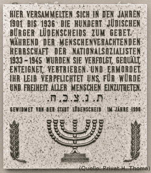 Foto: Eine Tafel. Text:'Hier versammelten sich in den Jahren 1901 bis 1936 die hundert jüdischen Bürger Lüdenscheids zum Gebet. Während der Menschenverachtenden Herrschaft der Nationalsozialisten 1933-1945 wurden sie verfolgt, gequält, enteignet, vertreiben und ermordet. Ihr Leid verpflichtet uns, für Würde und Freiheit aller Menschen einzutreten. Gewidmet von der Stadt Lüdenscheid im Jahre 1990'