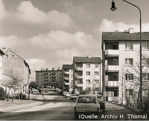 Foto: Eine Strasse mit Autos und Häusern.