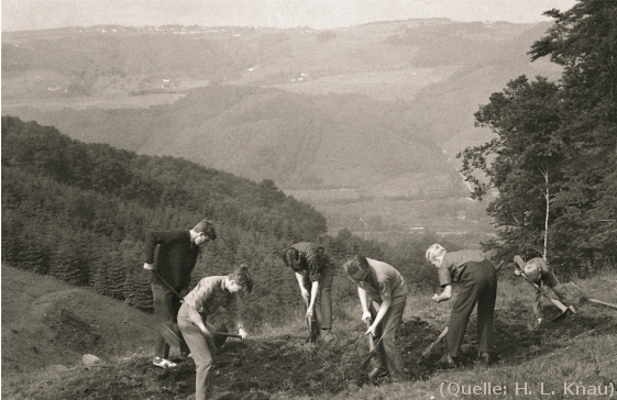 Foto: Ein Lehrer mit seinen Schülern bei archäologischen Ausgrabungen. Im Hintergrund sind Berge und Täler zu erkennen.